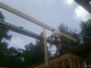Carpenter setting a ridge beam over a new addition frame — Ice Dam Removal by Roofing Brothers in Woodhaven