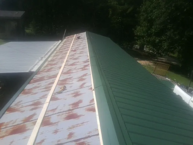 Old rusted panels beside newly installed green metal roofing — Wind Damage Roof Repair by Roofing Brothers in Woodhaven