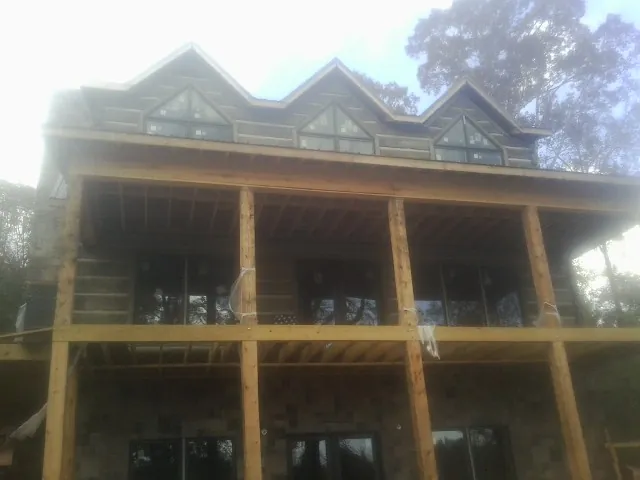 Dormers and porch framing on a large log home under construction — Roof Coating work by our crew in Woodhaven