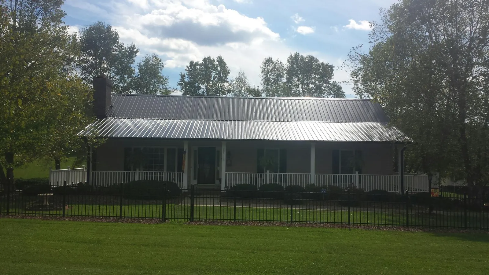 Gray metal roof on a brick ranch with a full width front porch — Gutter Guard Installation work by our crew in Woodhaven