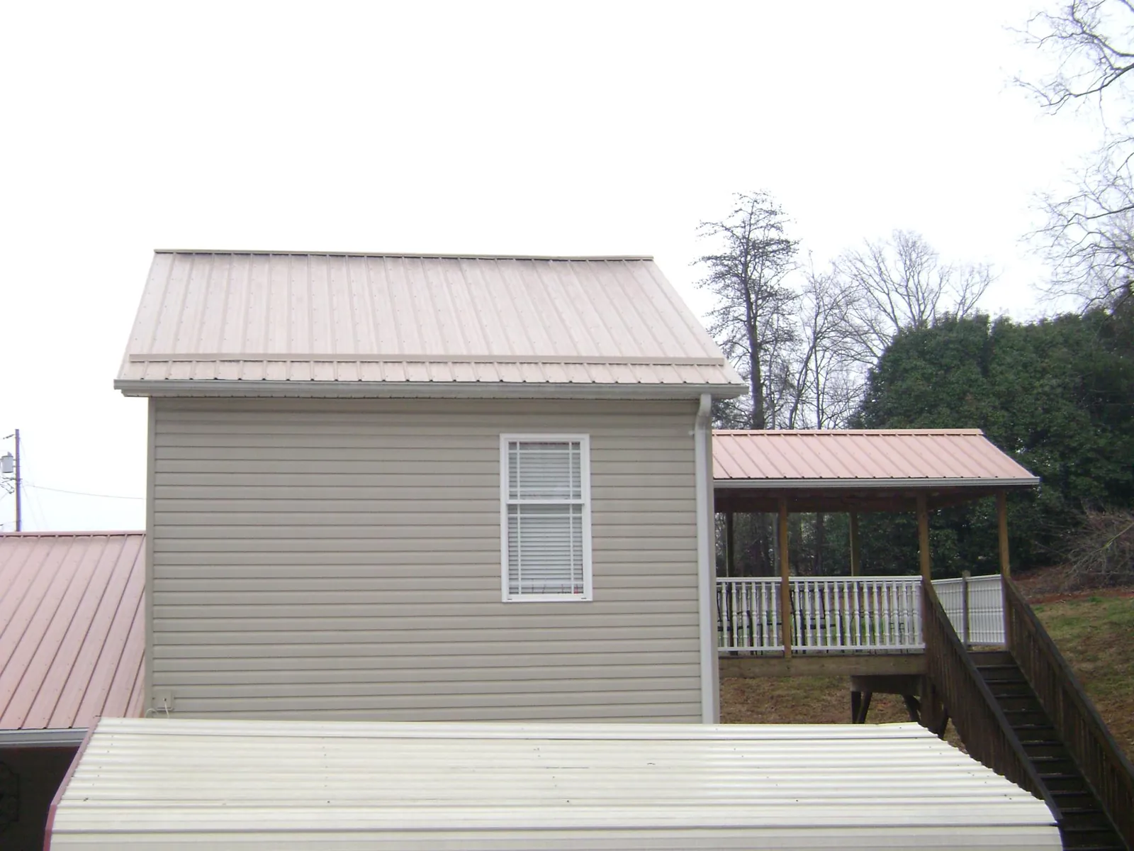 Tan metal roofs on a two story addition and attached porch, from a Roof Replacement job in Woodhaven