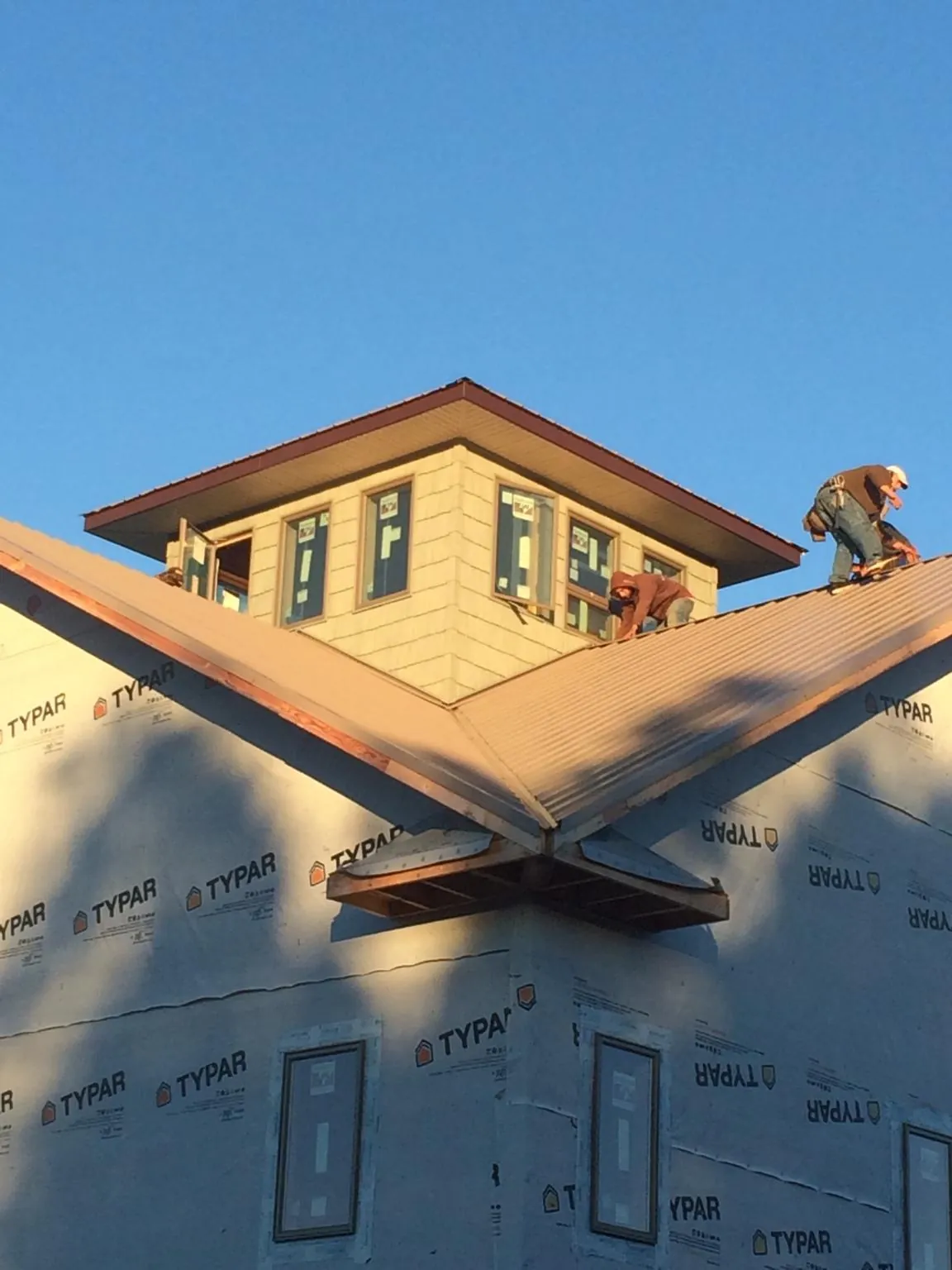 Roofers working around a rooftop cupola on a new metal roof at sunset — Roof Waterproofing in Woodhaven by Roofing Brothers